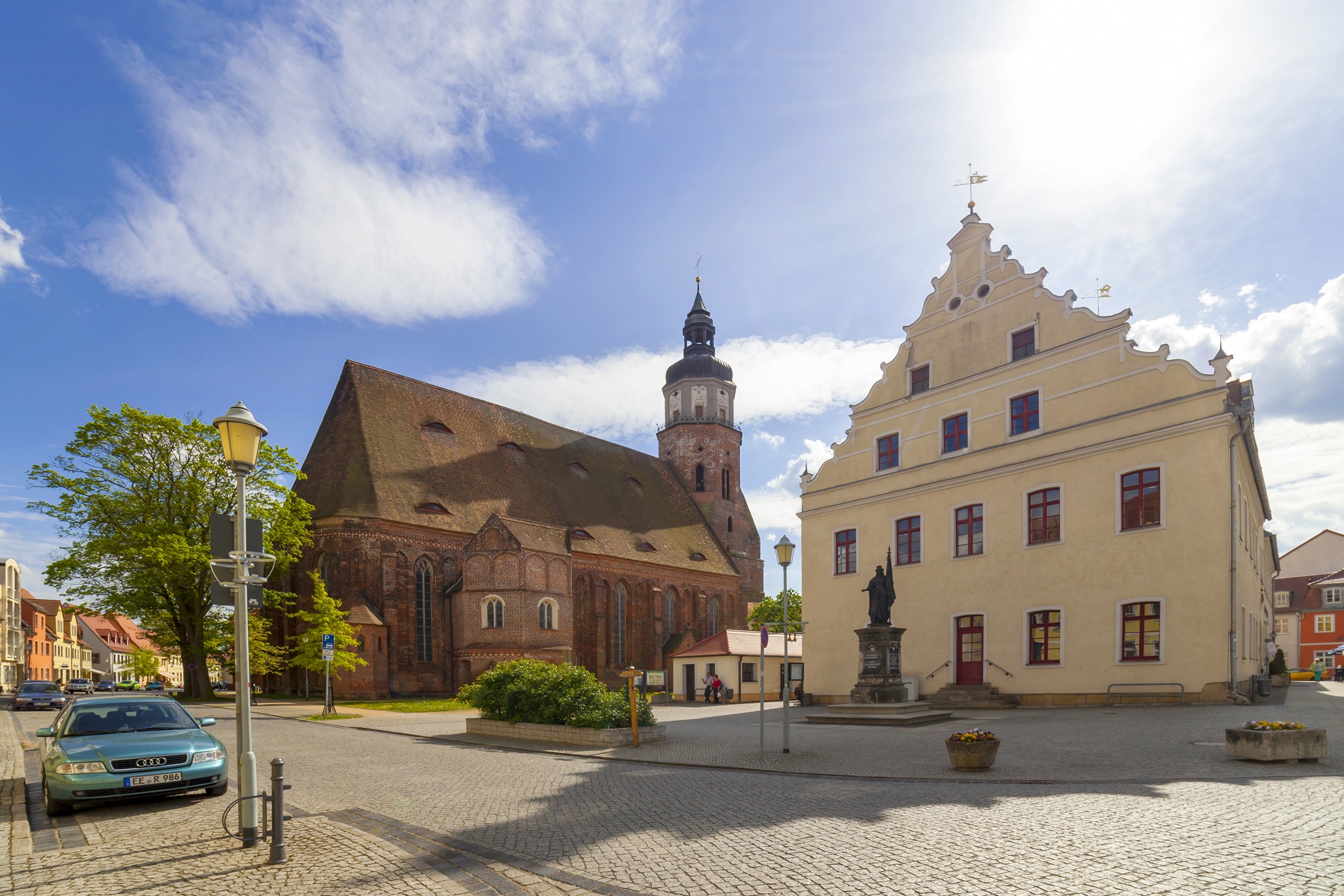Marktplatz mit Backsteinkirche, hellem Giebelhaus, Statue, Kopfsteinpflaster und blauem Himmel mit Wolken., Foto: Andreas Franke, Lizenz: Andreas Franke